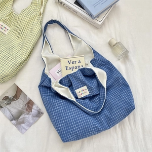 Close-up of blue and white checkered canvas tote bags on a minimalist fabric background