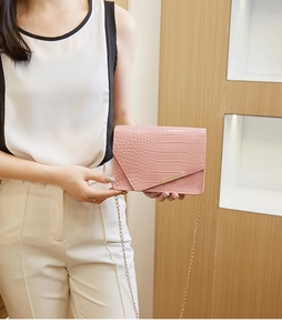 Detailed view of pink crocodile-embossed small square bag with gold chain strap