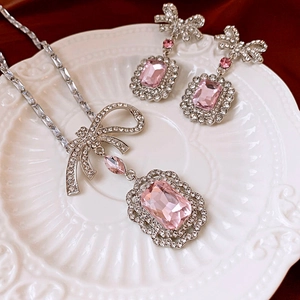 Detail view of crystal bow jewelry set with pink stones on a ceramic plate