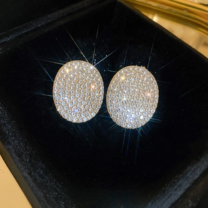 Macro shot of silver oval earrings with pavé set sparkling diamonds on black velvet