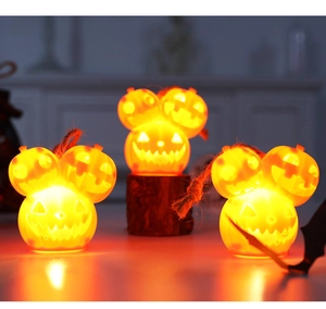 Close-up of three glowing stacked orange pumpkin lanterns with a rustic hemp rope loop