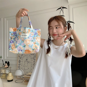 Détail du sac cabas en toile à fleurs avec des motifs oranges et violets sur bleu