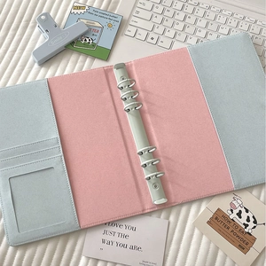 Detail of pink and blue 6-ring PU binder interior with card slots and metal binder clip