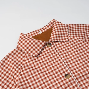 Gros plan d'un trench-coat à carreaux vichy rouge et blanc avec boutons en écaille