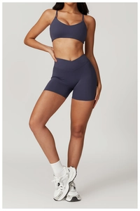 Detail of high-waist crossover waistband on dark gray yoga shorts and sports bra set