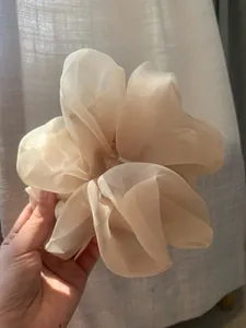 Detail of a large beige organza scrunchie with soft pleats and elegant mesh texture