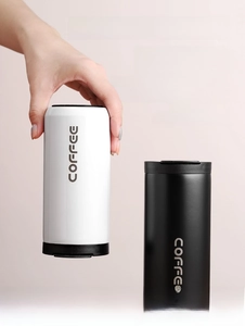 Close-up of black matte and white glossy stainless steel coffee tumblers with lids