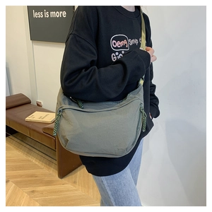 Detail of olive green canvas messenger bag featuring a minimalist drawstring design and strap