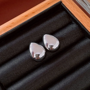 Macro view of silver teardrop earrings on black velvet padding inside a gift box