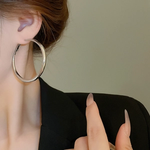 Close-up of minimalist large silver hoop earrings worn by a model in a black blazer