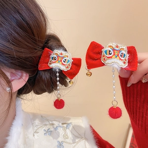 Detail of red velvet hair clips with embroidered lion dance design and pearl tassels