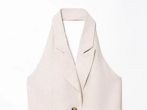 Dettaglio del gilet in lino beige con revers a lancia e chiusura con bottone ambrato