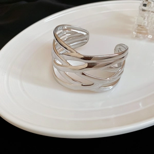 Detailed view of silver hollow multi-layer crossover open cuff bracelet on white ceramic tray