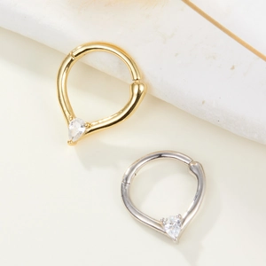 Détails macro des boucles d'oreilles cœur et goutte avec zircone sur fond de marbre