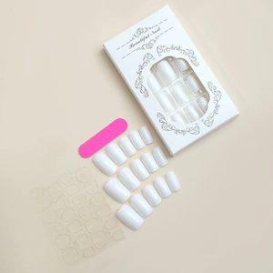 Macro detail of glossy white square press-on nail kit with pink file and adhesive tabs