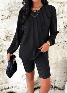 Detail of black ribbed knit two-piece set featuring long-sleeve top and cycling shorts