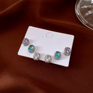 Detailed view of silver stud earrings set with purple, teal and clear oval crystals