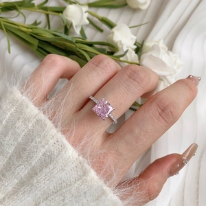 Close-up of a square princess cut pink gemstone ring with side diamonds on model's hand