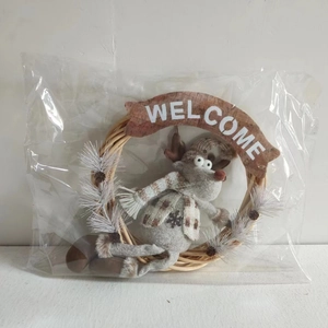 Close-up of a Christmas rattan wreath with a reindeer plush and a Welcome sign in packaging