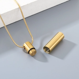 Detail of gold cylindrical pendant showing open screw cap and hollow storage space