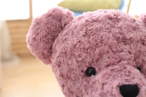 Close-up of pink teddy bear plush with soft rose-swirl texture and fluffy fur detail