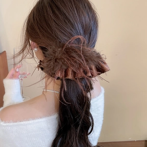 Detailed back view of a brown velvet hair scrunchie with elegant feather fringe accents