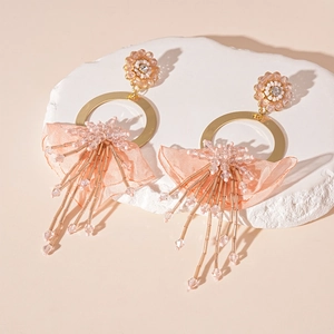 Detail of pink lace flower earrings with beads, gold hoops and long fringe tassels