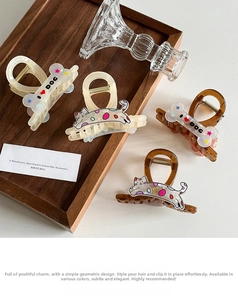 Detail of acetate hair claws featuring cute cat patterns and dog bone shapes in a tray