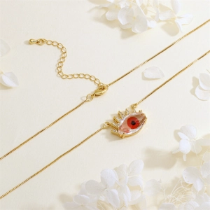 Detail of gold plated Evil Eye pendant with red bead and white cubic zirconia stones