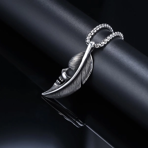 Vintage silver punk skull feather pendant necklace with steel bead chain on dark display
