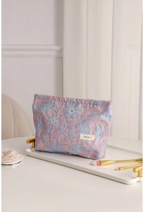 Dettaglio della trousse jacquard rosa con etichetta H&R BAG su vassoio bianco