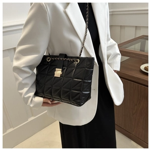 Détail d'un sac cabas noir matelassé avec chaîne dorée et boucle carrée en métal