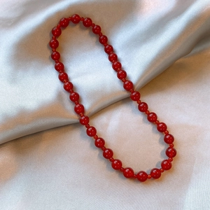 Macro detail of glossy red agate beads on premium silver silk background fabric