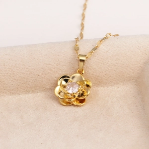 Macro detail of a golden flower pendant with a sparkling gemstone on a wavy water chain