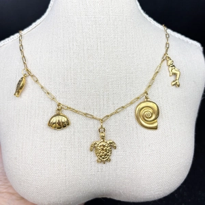 Detail of 18K gold-plated necklace with fish, shell, turtle and mermaid charms