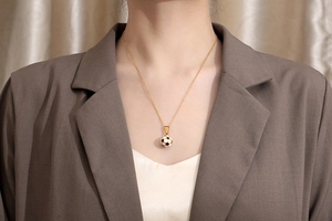 Macro shot of gold-plated titanium steel necklace with soccer ball enamel pendant