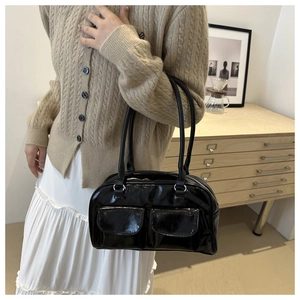 Detail of glossy black patent leather shoulder bag with double front flap pockets