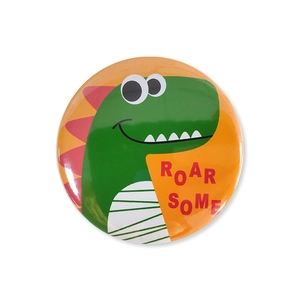 Close-up of a green cartoon dinosaur tinplate badge with Roarsome text for kids party