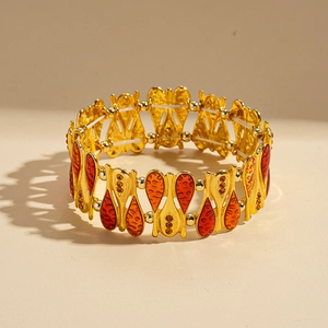 Dettaglio di un bracciale dorato boho con ciondoli a goccia rossi e arancioni