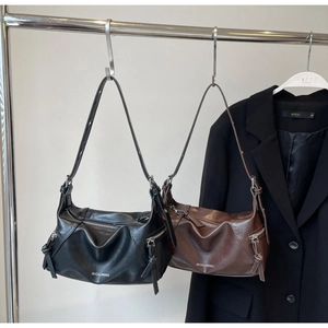 Detail of black and brown pleated shoulder bags with side zippers and smooth texture