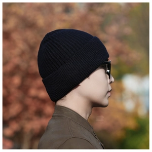Side view of a navy blue ribbed knit beanie worn by a male model in an outdoor setting
