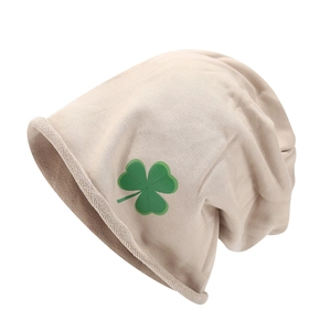 Détail du bonnet en maille côtelée beige avec un motif de trèfle vert éclatant