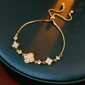 Detail of gold adjustable clover bracelet with clear zircon on a green jewelry box
