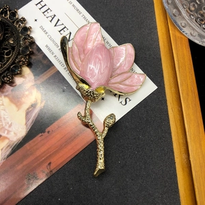 Elegant floral brooch featuring pink enamel magnolia flower with gold metal leaves
