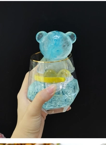 Vista macro de un cubito de hielo azul con forma de oso en un vaso hexagonal dorado