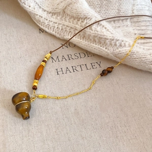 Close-up of tiger eye gourd pendant with wooden beads on a textured canvas background
