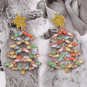 Macro shot of colorful rhinestone Christmas tree earrings on a vintage portrait background