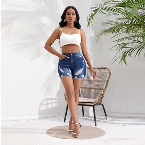 Detail of high waisted distressed denim shorts with frayed hems and slim fit white tank top