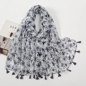 Close-up of ink floral print scarf with soft gray tassel fringe and lightweight texture