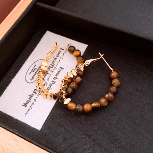 Close-up of 18k gold plated hoop earrings with brown tiger eye beads in a black jewelry box